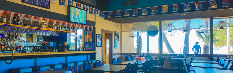 tables and chairs inside bar with televisions playing sports